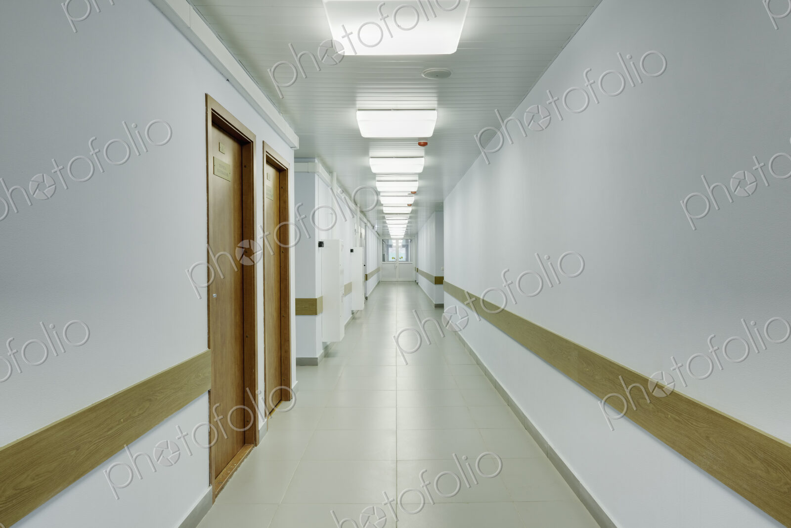 Brightly lit corridor in a sports hall with doors leading off it.