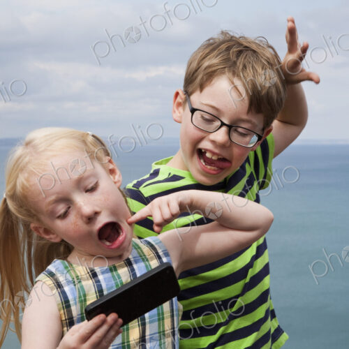 Brother and sister making faces and taking a selfie with a smart phone. Brother and sister making faces and taking a selfie with a smart phone.