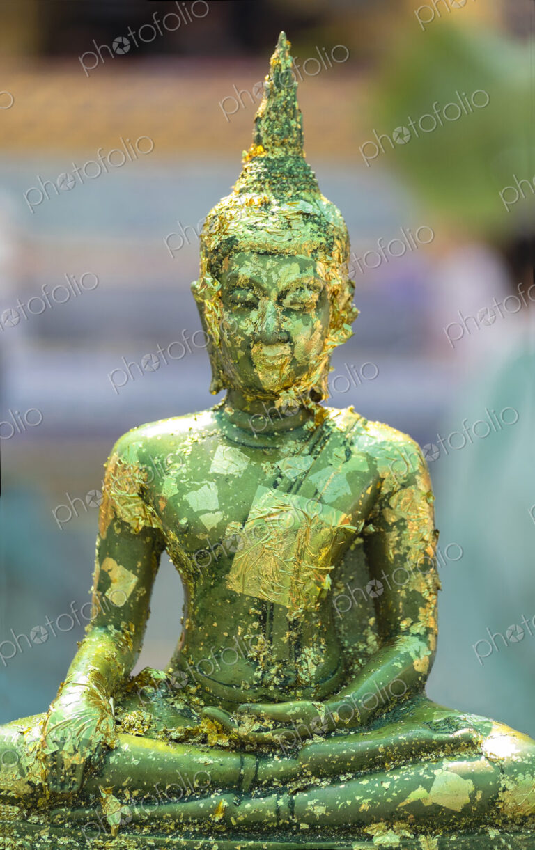 Buddha statue with gold leaf flaking at the Grand Palace Bangkok.