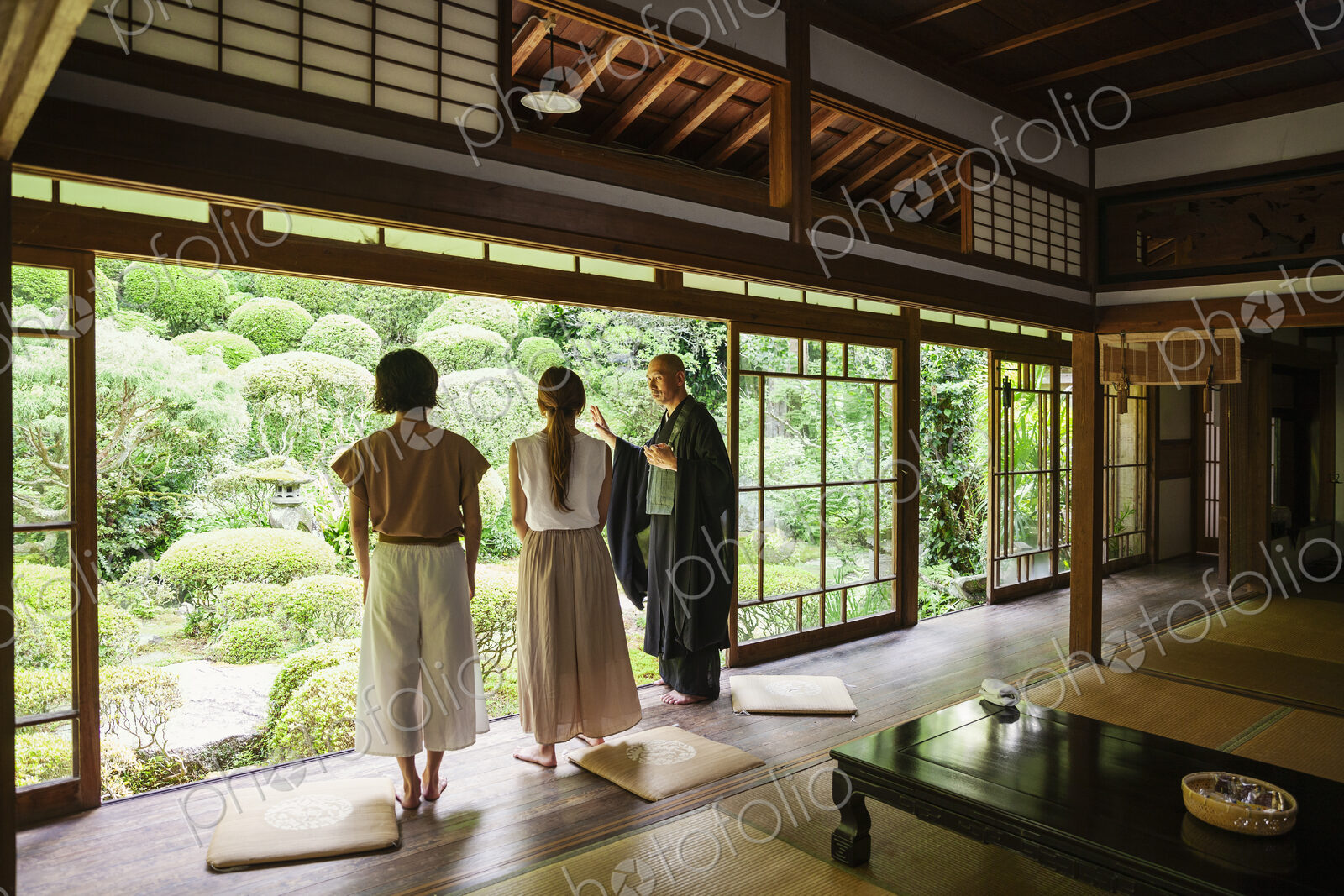 Buddhist priest and two Japanese women standing in Buddhist temple.