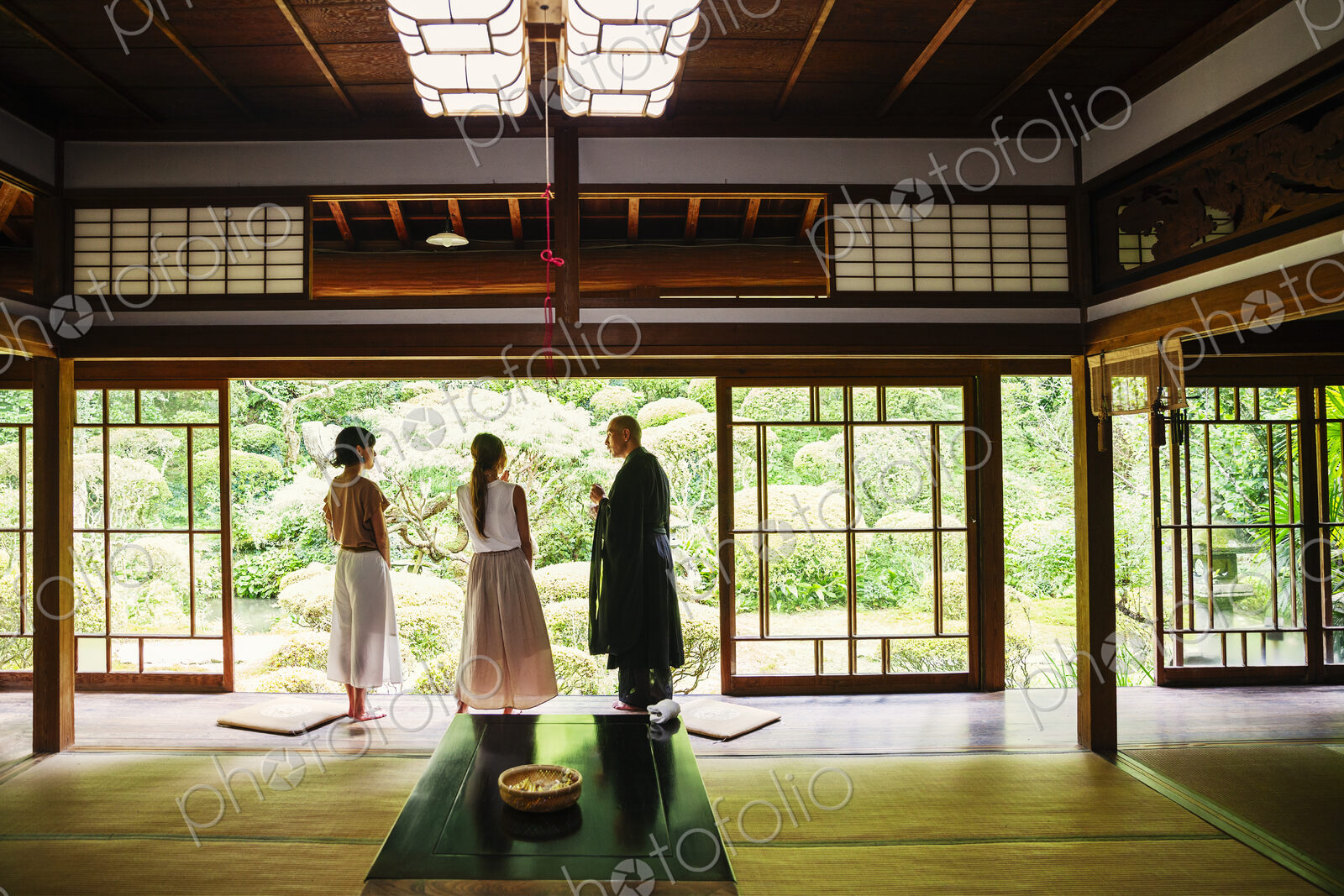 Buddhist priest and two Japanese women standing in Buddhist temple.
