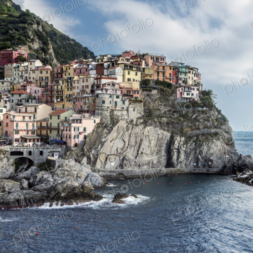 Buildings on rocky Manarola coastline and ocean, La Spezia, Italy