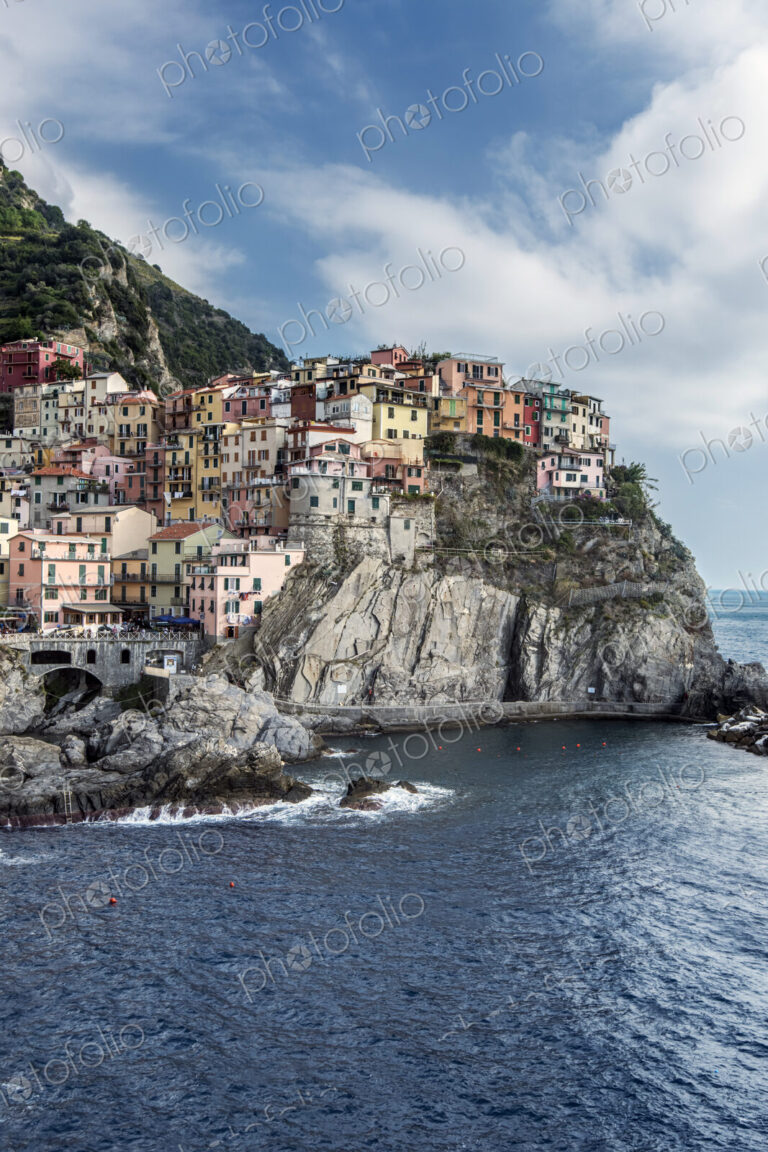 Buildings on rocky Manarola coastline and ocean, La Spezia, Italy