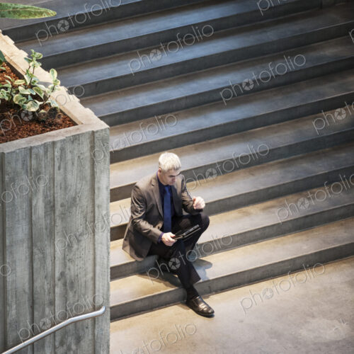 Busienssman working on a notebook computer while sitting on the steps of a convention… Busienssman working on a notebook computer while sitting on the steps of a convention…