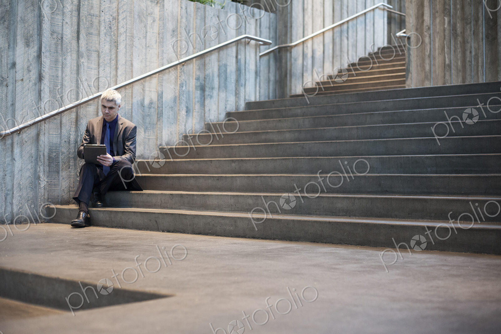 Busienssman working on a notebook computer while sitting on the steps of a convention…