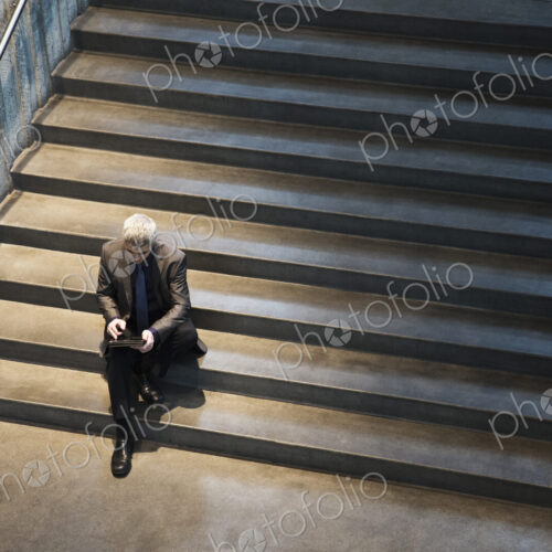Busienssman working on a notebook computer while sitting on the steps of a convention… Busienssman working on a notebook computer while sitting on the steps of a convention…