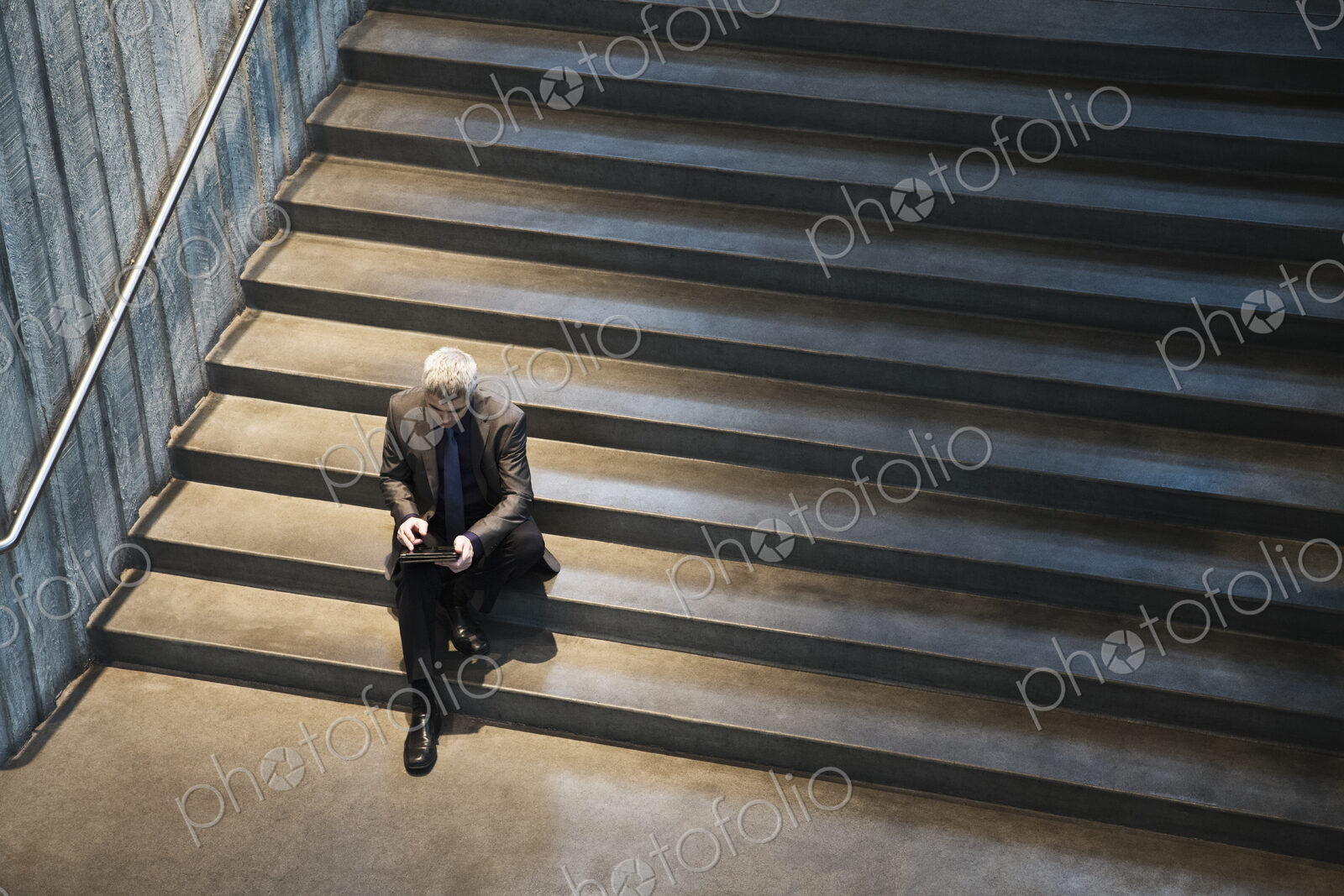 Busienssman working on a notebook computer while sitting on the steps of a convention…