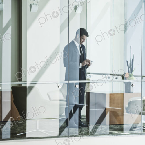 Businesman stading behind a conference room window in a large business center. Businesman stading behind a conference room window in a large business center.