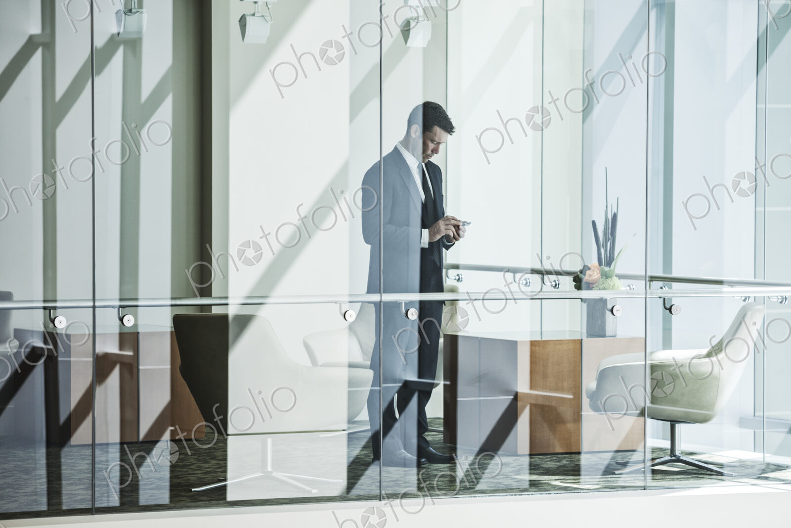 Businesman standing behind a conference room window in a large business center.