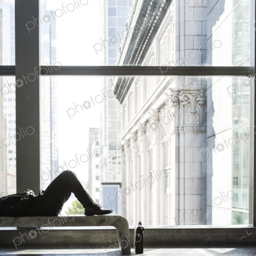 Business man taking a break laying on a bench in a large open lobby area. Business man taking a break laying on a bench in a large open lobby area.