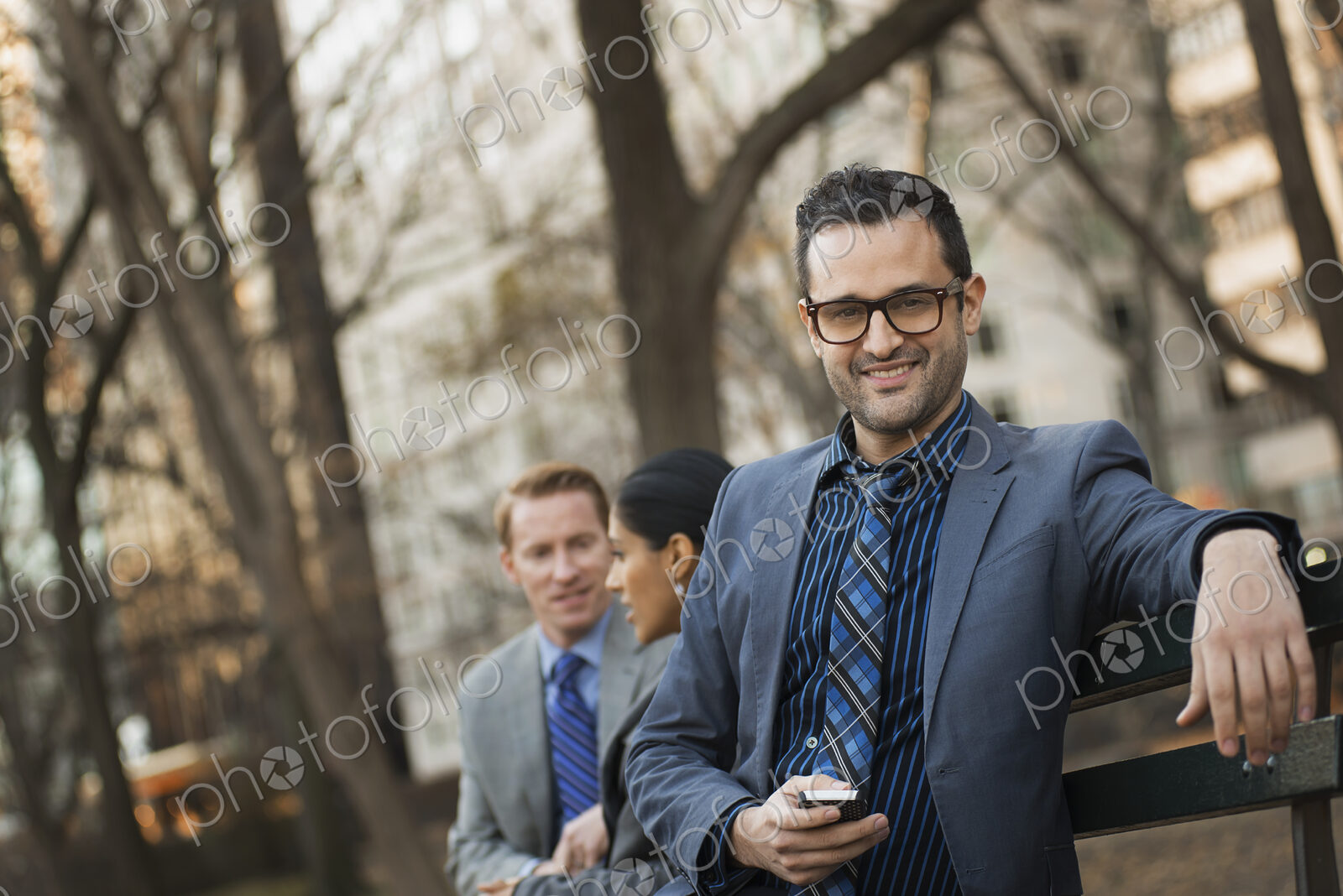 Business people in the city. Three people, two men and a woman in a city park relaxing.