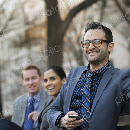 Business people in the city. Three people, two men and a woman in a city park relaxing. Business people in the city. Three people, two men and a woman in a city park relaxing.