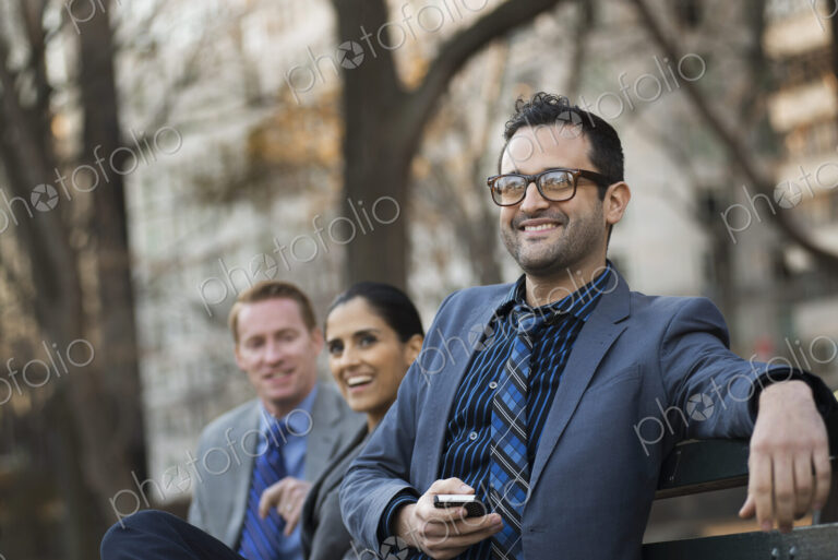 Business people in the city. Three people, two men and a woman in a city park relaxing.