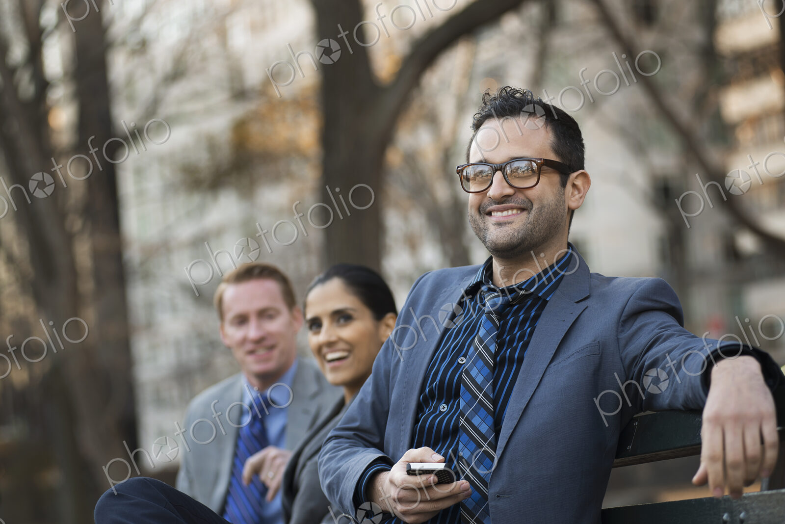 Business people in the city. Three people, two men and a woman in a city park relaxing.
