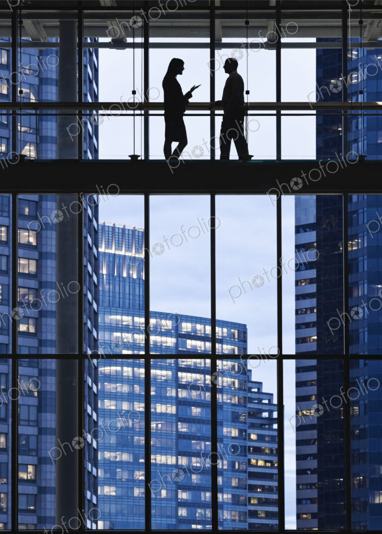 Business people meeting on an elevated walkway between office buildings.