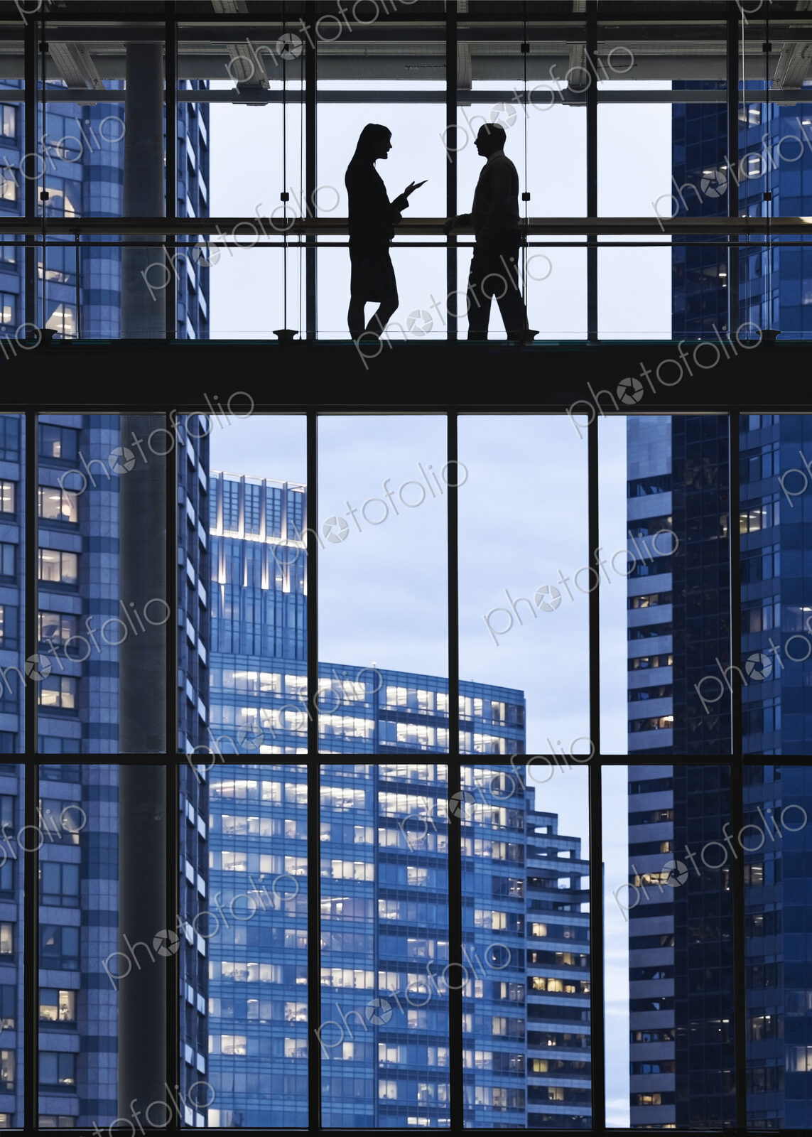 Business people meeting on an elevated walkway between office buildings.
