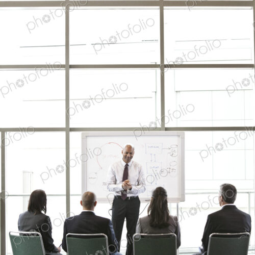 Business people sitting and watching a presentation on a white board Business people sitting and watching a presentation on a white board