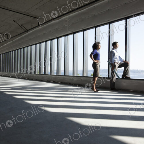 Business woman and man standing in a new empty raw office space.