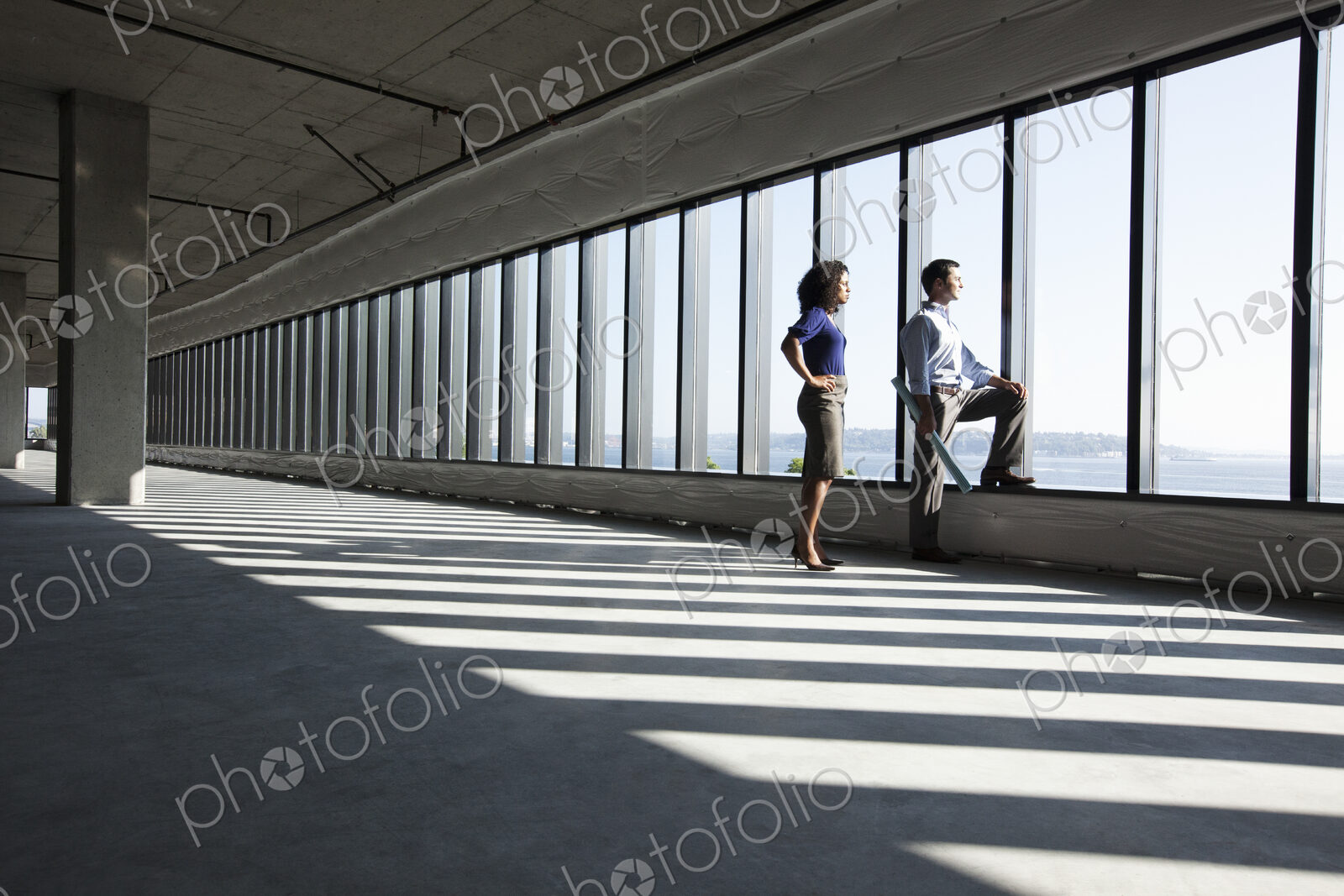 Business woman and man standing in a new empty raw office space.