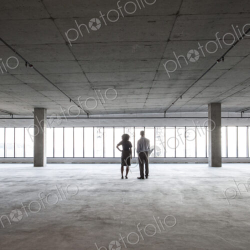 Business woman and man standing in a new empty raw office space. Business woman and man standing in a new empty raw office space.