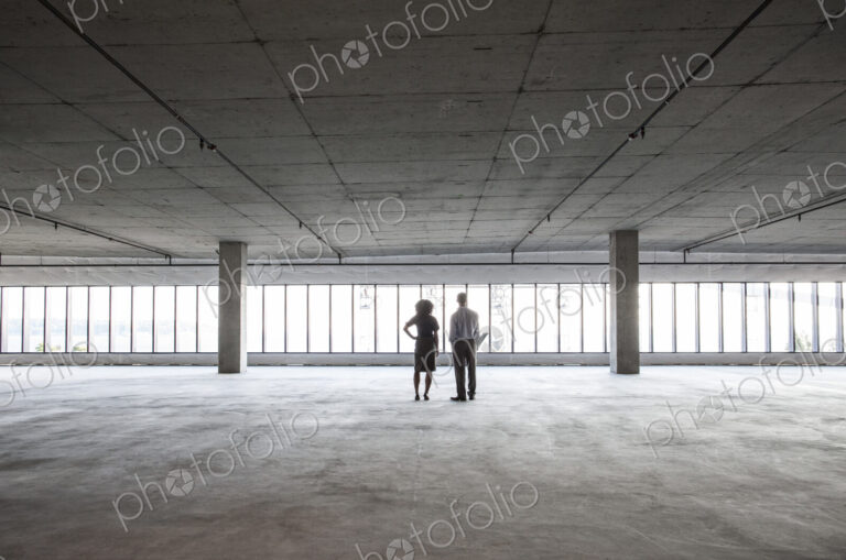 Business woman and man standing in a new empty raw office space.