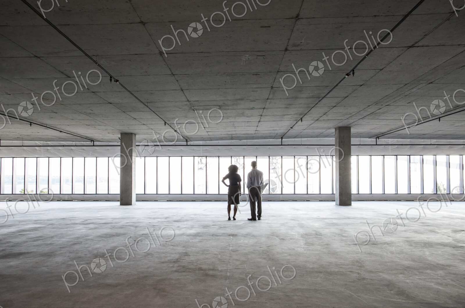 Business woman and man standing in a new empty raw office space.