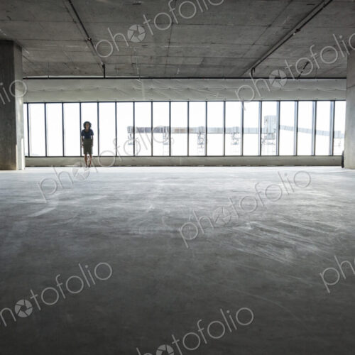 Business woman standing near windows in a new empty raw office space.