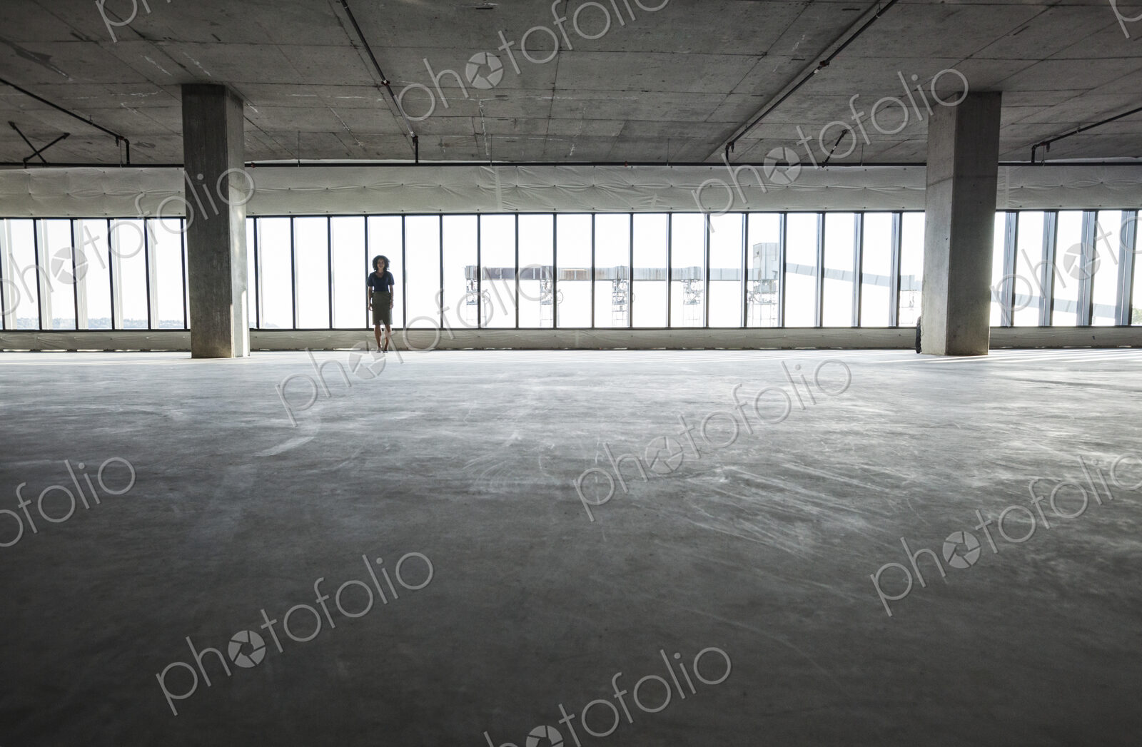 Business woman standing near windows in a new empty raw office space.