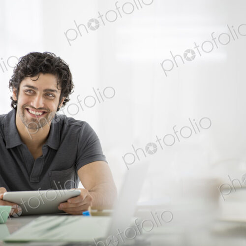 Business. A light airy office environment. A man sitting holding a digital tablet. Business. A light airy office environment. A man sitting holding a digital tablet.