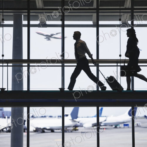 Businessman and business woman running to catch an airplane on an airport walkway. Businessman and business woman running to catch an airplane on an airport walkway.