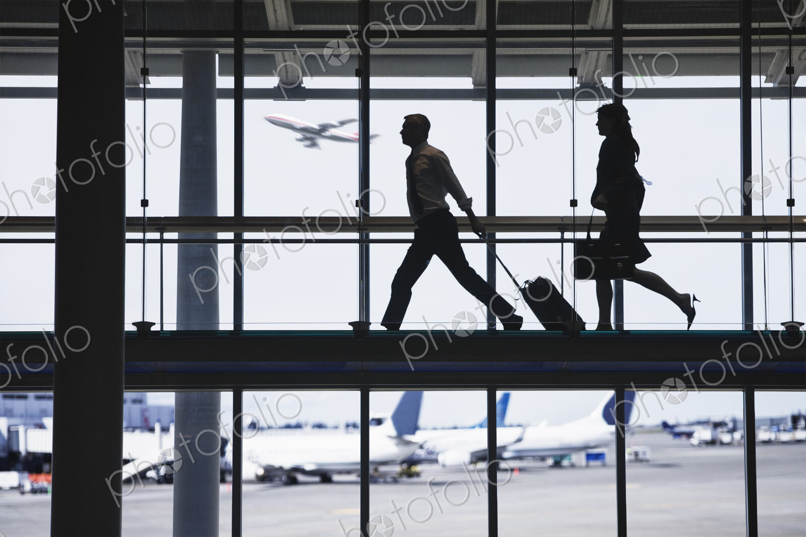 Businessman and business woman running to catch an airplane on an airport walkway.