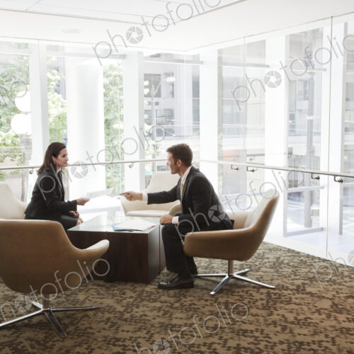Businessman and woman meeting at a table in a large business center. Businessman and woman meeting at a table in a large business center.