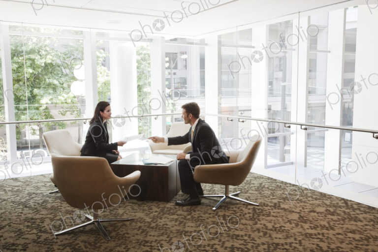 Businessman and woman meeting at a table in a large business center.