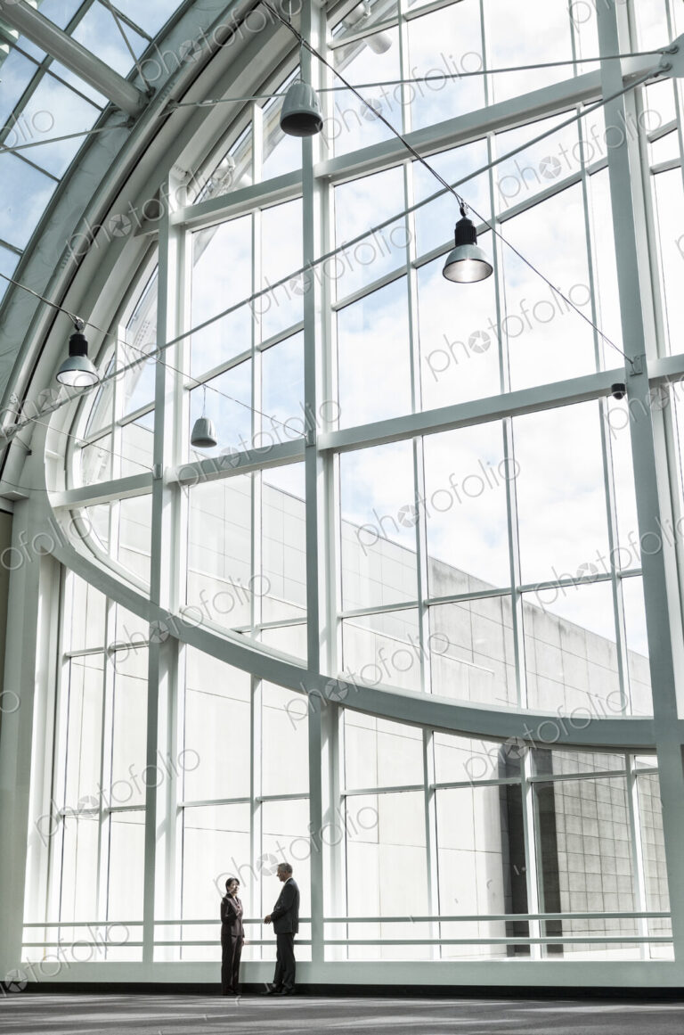 Businessman and woman meeting in a large glass covered walkway