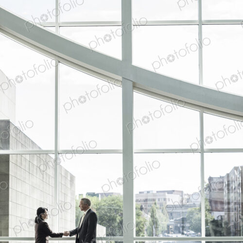 Businessman and woman meeting in a large glass covered walkway