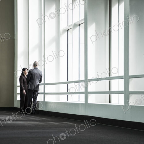 Businessman and woman meeting in a large glass covered walkway Businessman and woman meeting in a large glass covered walkway