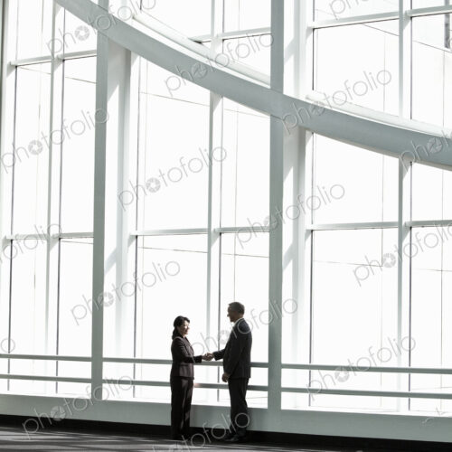 Businessman and woman meeting in a large glass covered walkway