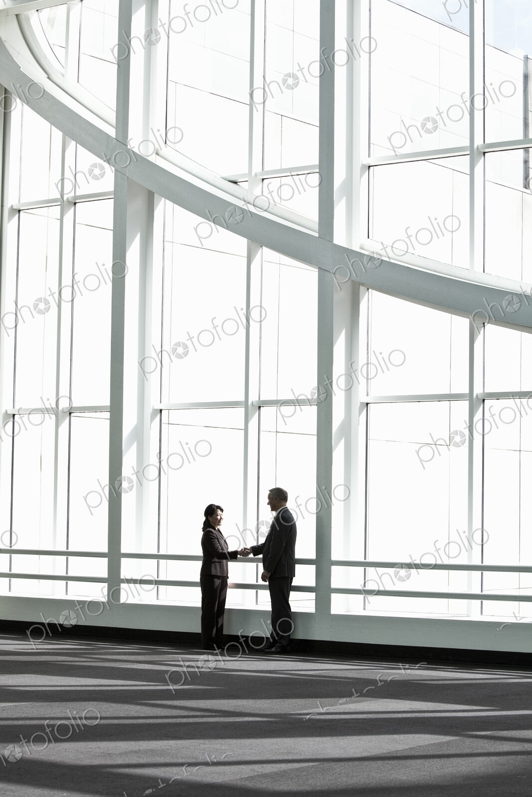 Businessman and woman meeting in a large glass covered walkway