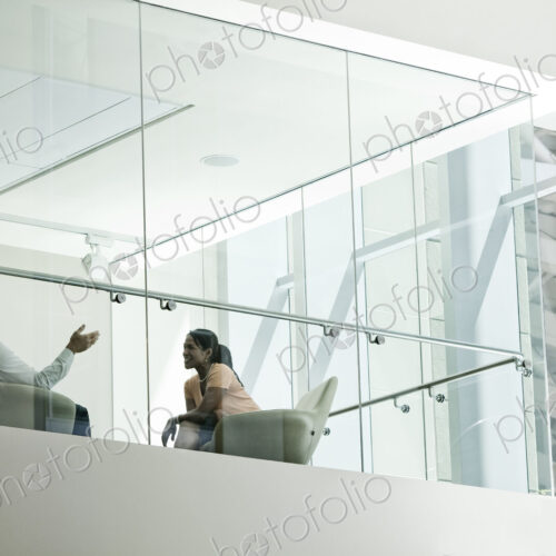 Businessman and woman standing behind a conference room window ina large business center. Businessman and woman standing behind a conference room window ina large business center.