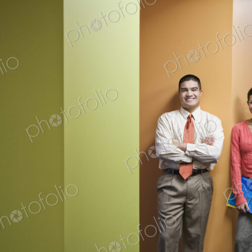 Businessman and woman standing in a hallway next to very colorful office walls.