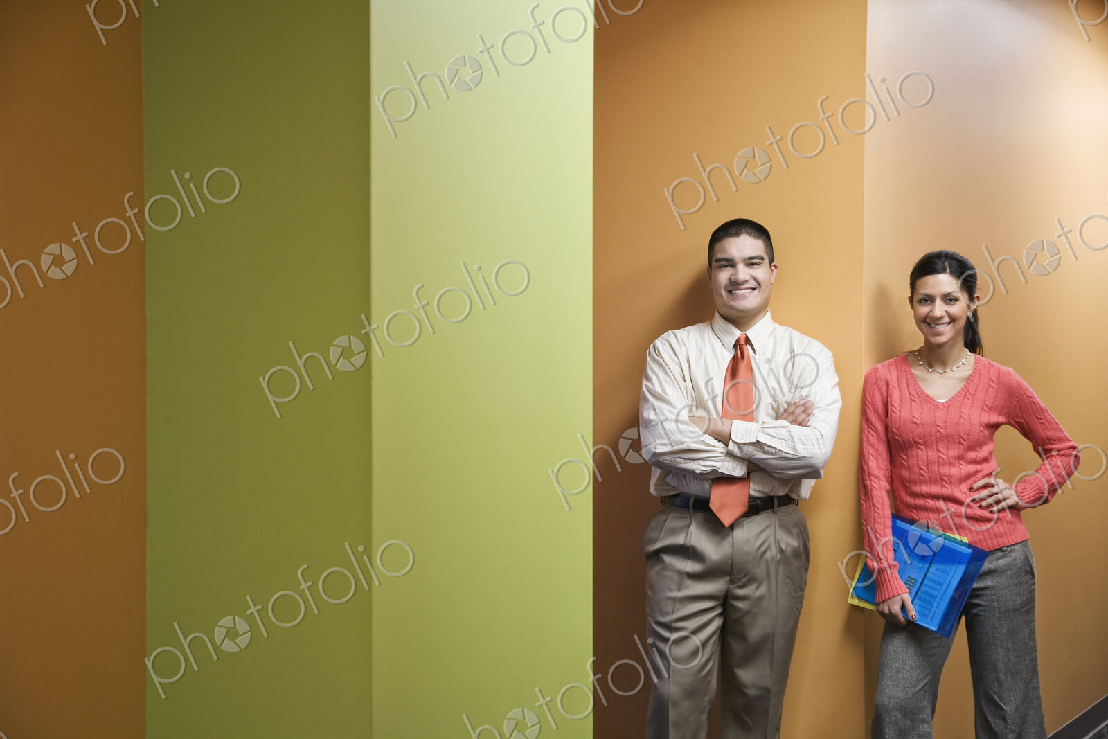 Businessman and woman standing in a hallway next to very colorful office walls.