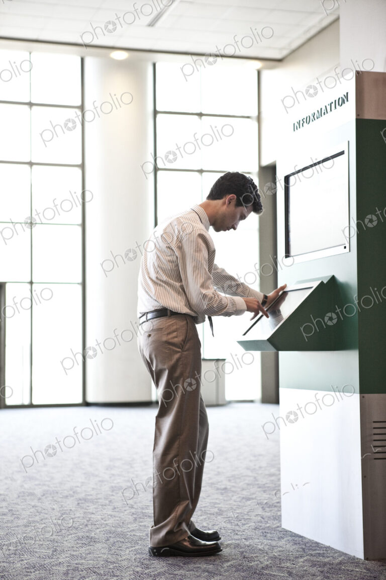 Businessman at an information kiosk in a large lobby area.
