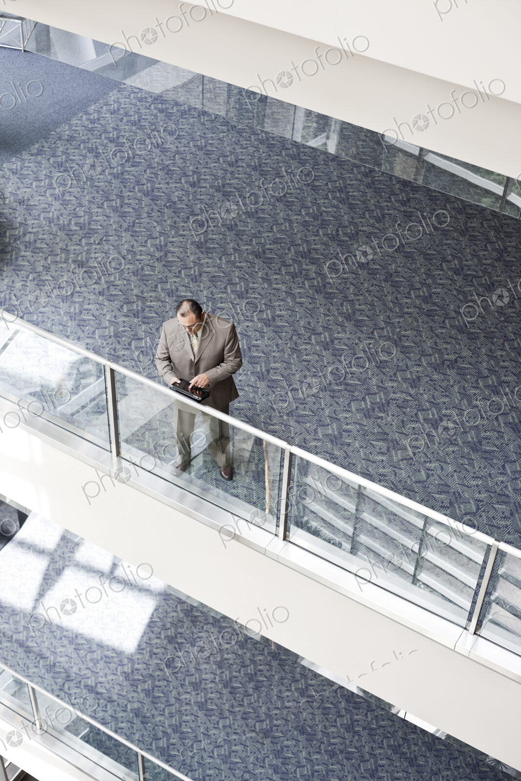 Businessman checking his notebook computer on a walkway, high angle view