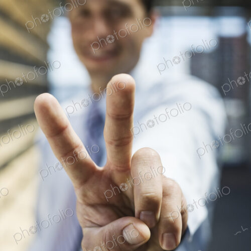 Businessman gesturing a victory sign to the camera.