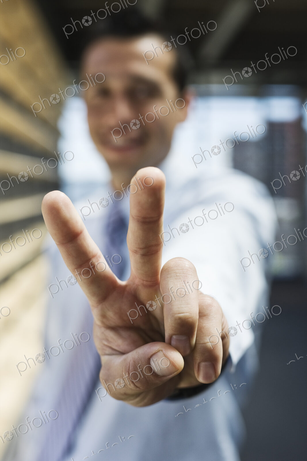 Businessman gesturing a victory sign to the camera.