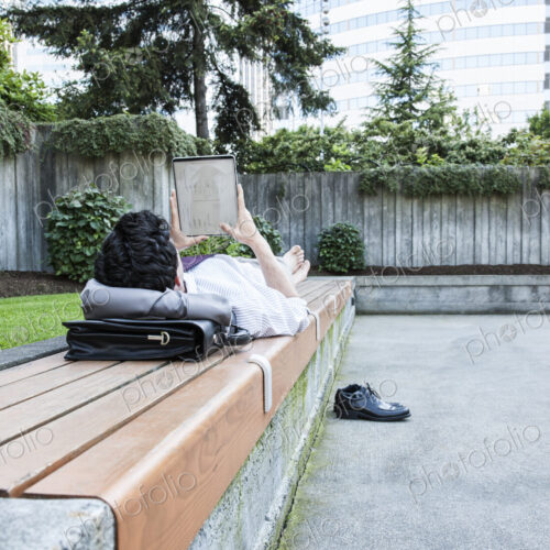 Businessman in a downtown city park taking a break and checking his computer notebook