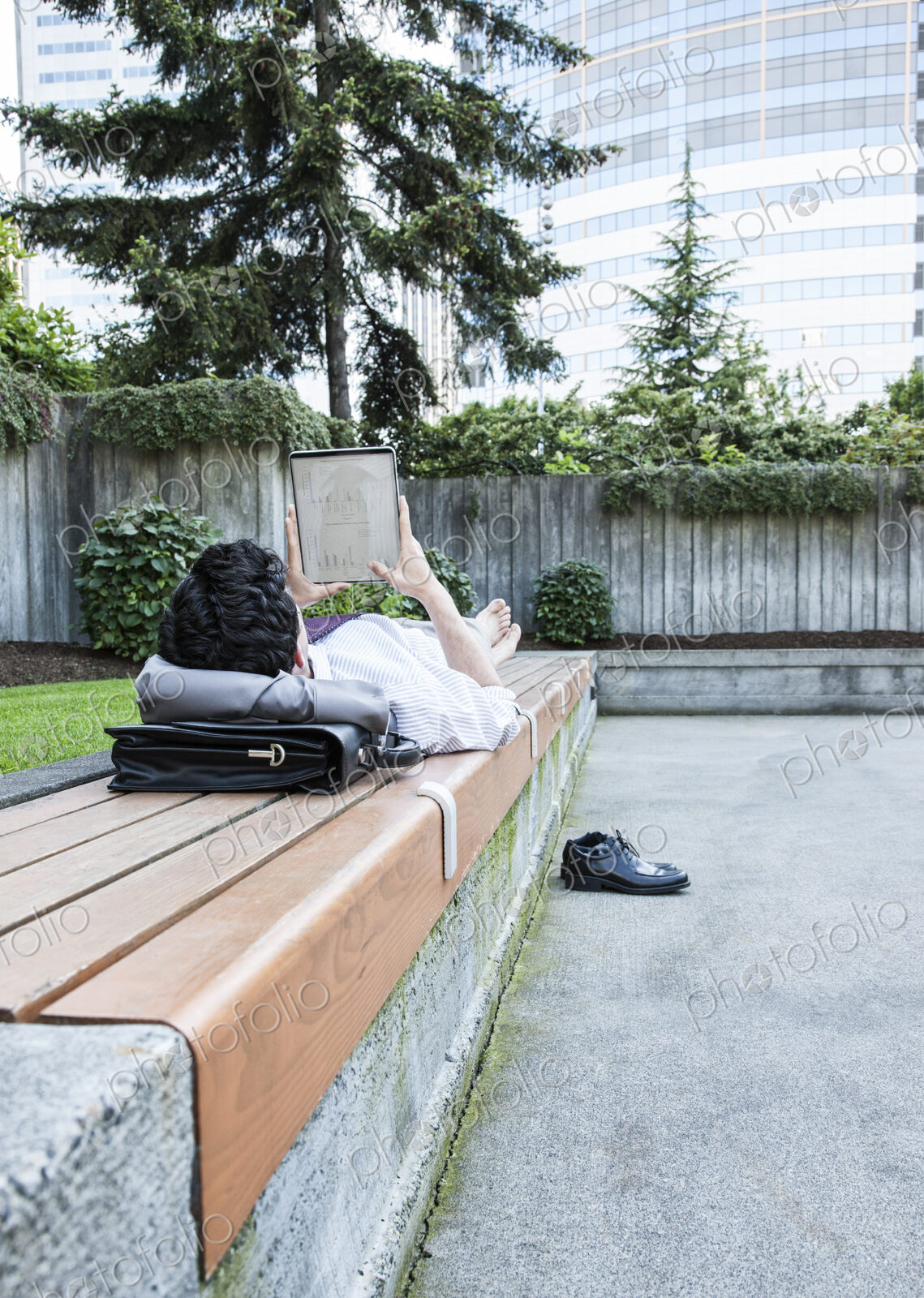 Businessman in a downtown city park taking a break and checking his computer notebook