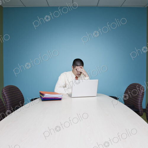 Businessman in a stressful situation sitting at a table in a conference room. Businessman in a stressful situation sitting at a table in a conference room.
