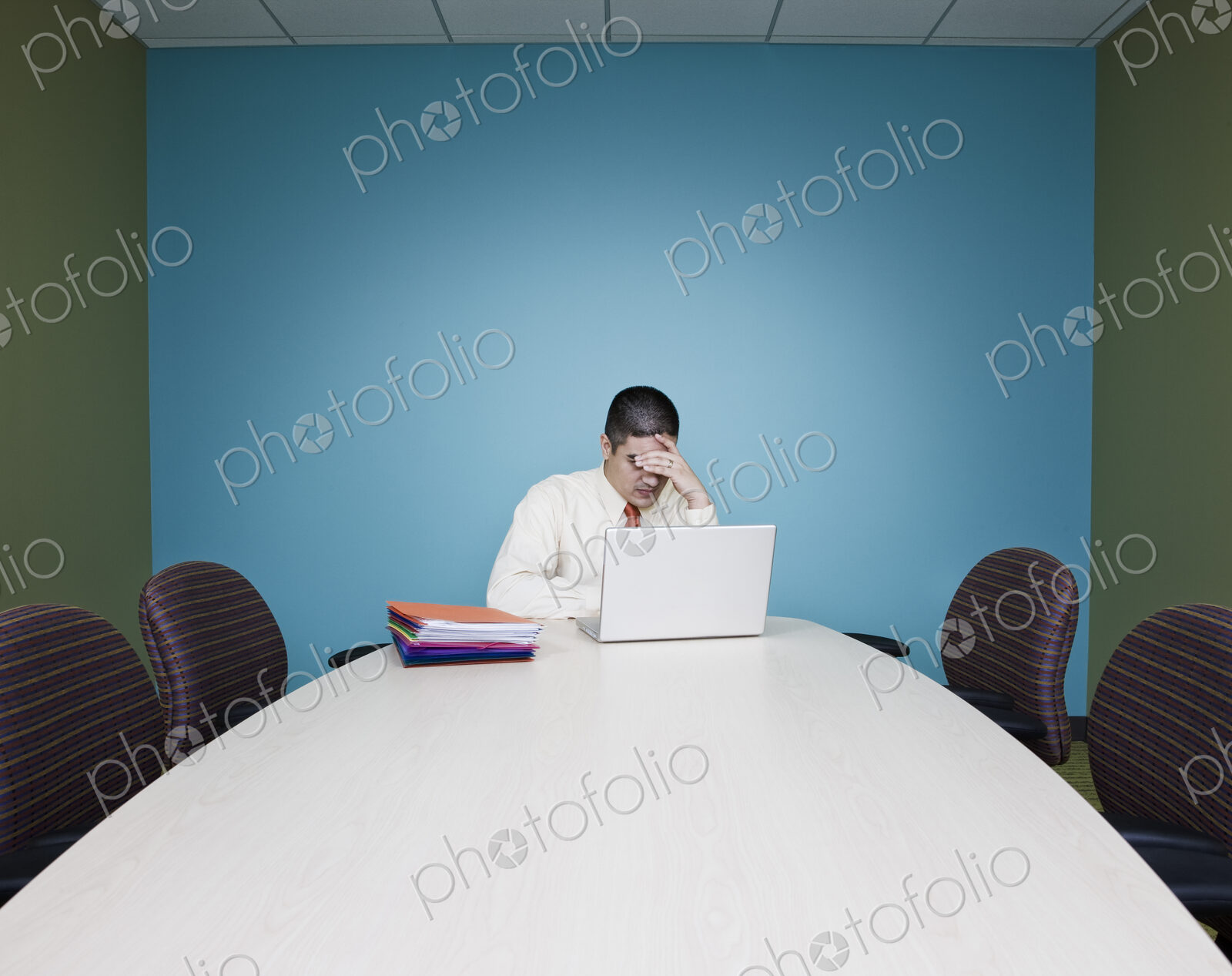 Businessman in a stressful situation sitting at a table in a conference room.