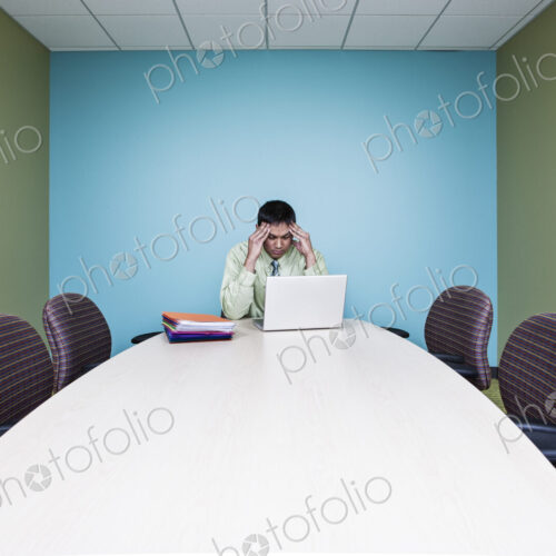 Businessman in a stressful situation sitting at a table in a conference room. Businessman in a stressful situation sitting at a table in a conference room.